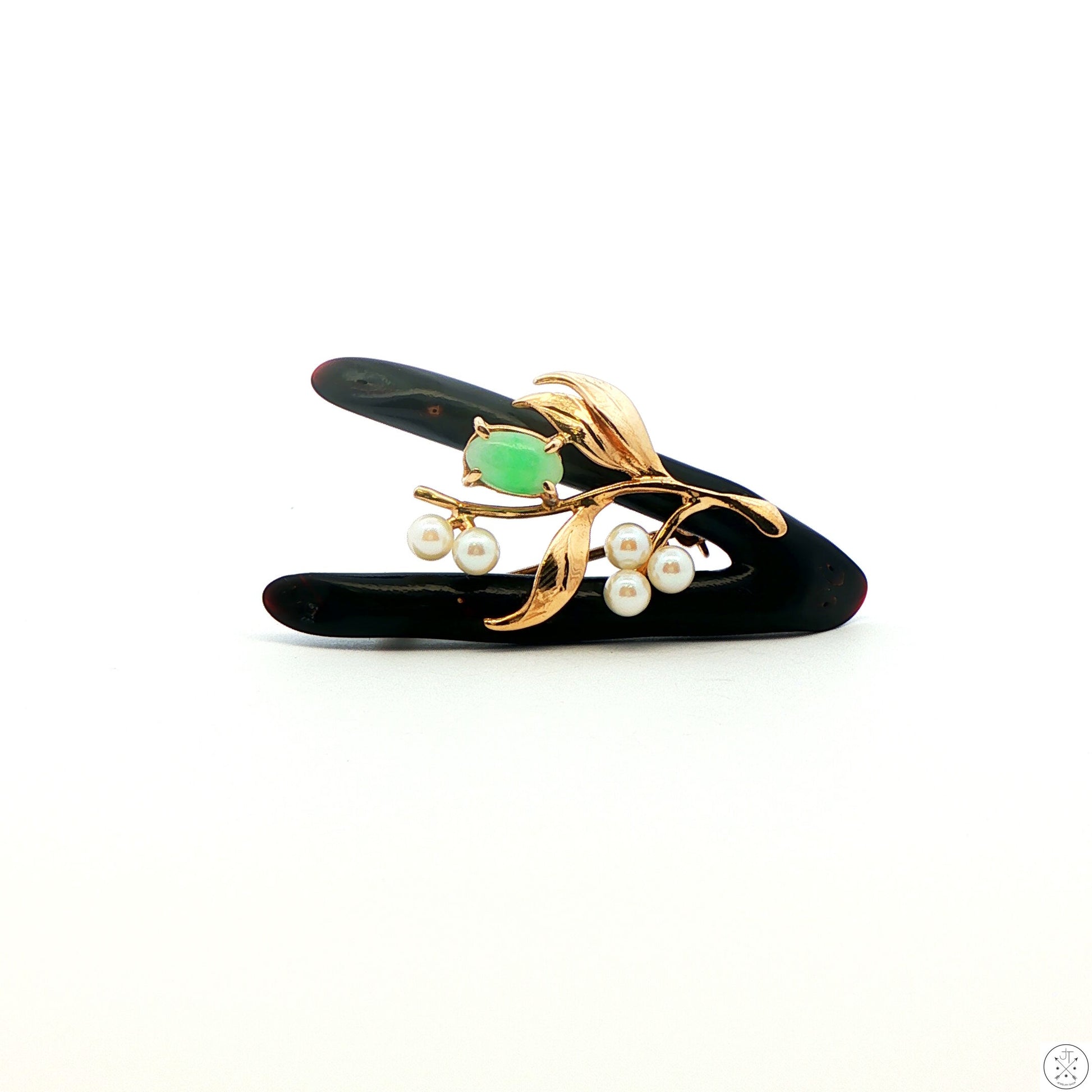 Vintage black coral brooch with 14k gold, green jade, and pearls against a white background.