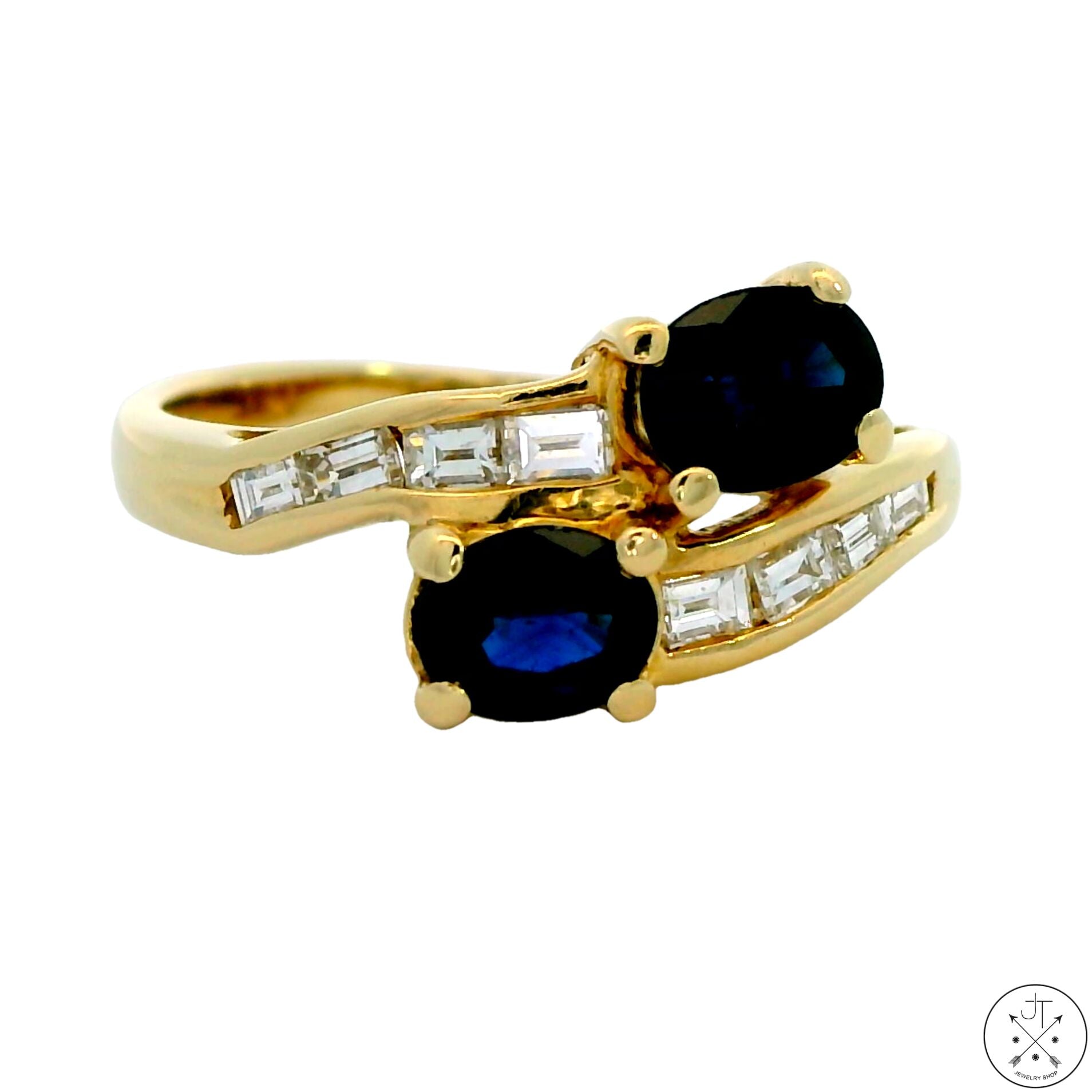 A 14k yellow gold bypass ring with two London blue topaz gemstones and a row of emerald cut diamonds.