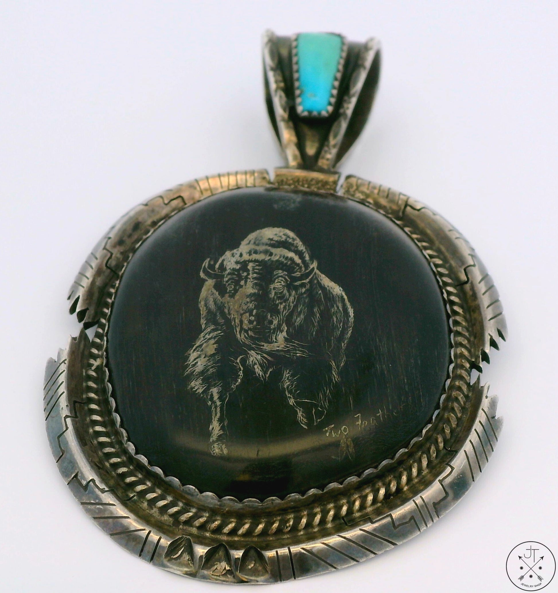 A Sterling Silver pendant featuring a Bison engraving with a turquoise gemstone bezel, surrounded by a textured silver frame.