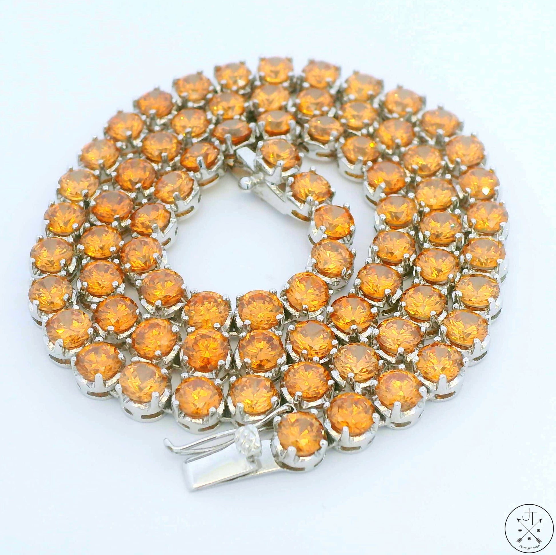 A sterling silver tennis necklace with 74 orange cubic zirconia stones, featuring a secure locking clasp.