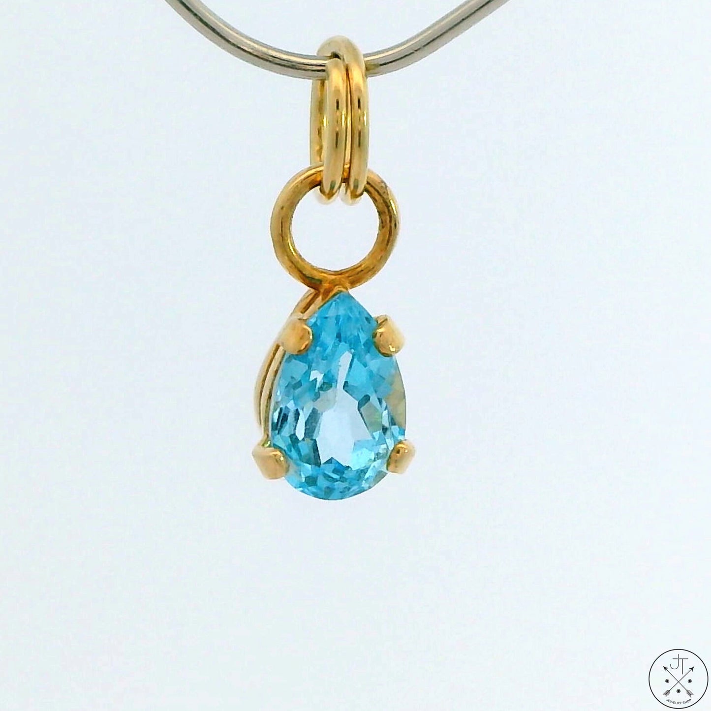 A 14k yellow gold split ring bale with a blue topaz charm attached to it.