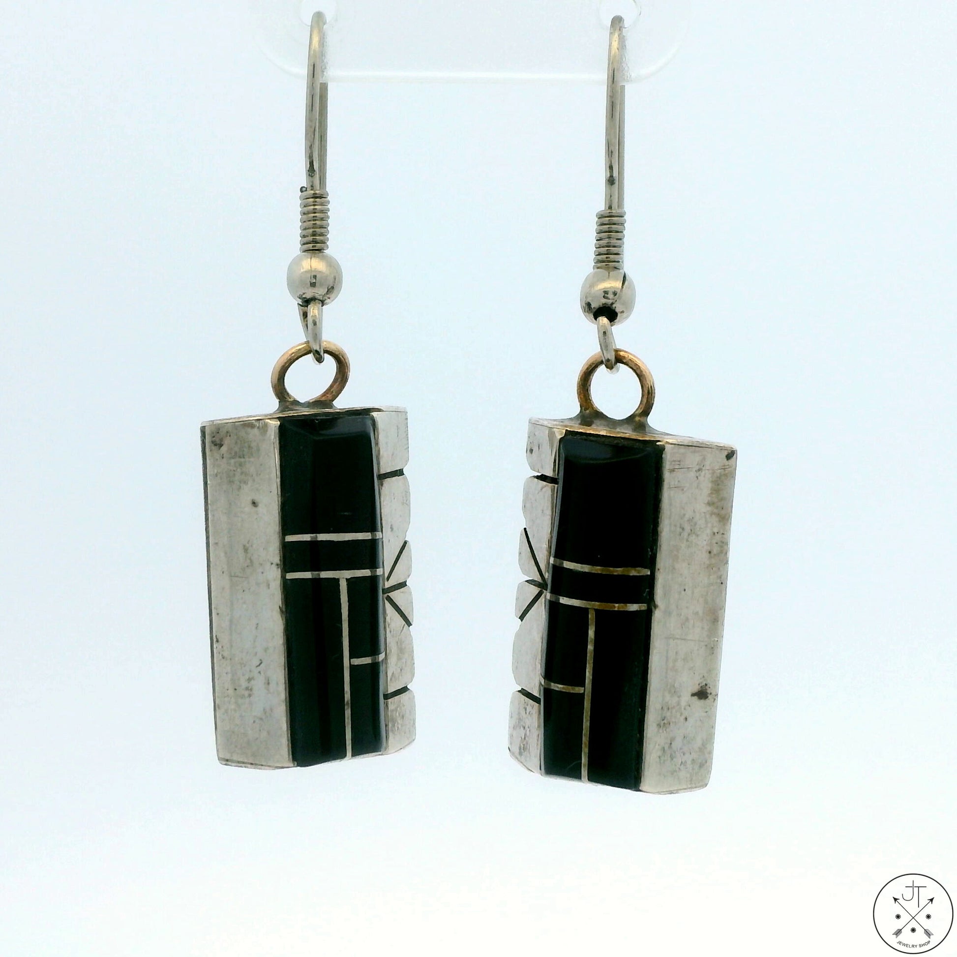A pair of vintage Navajo sterling silver dangle earrings with black onyx inlay, signed, displayed against a white background.