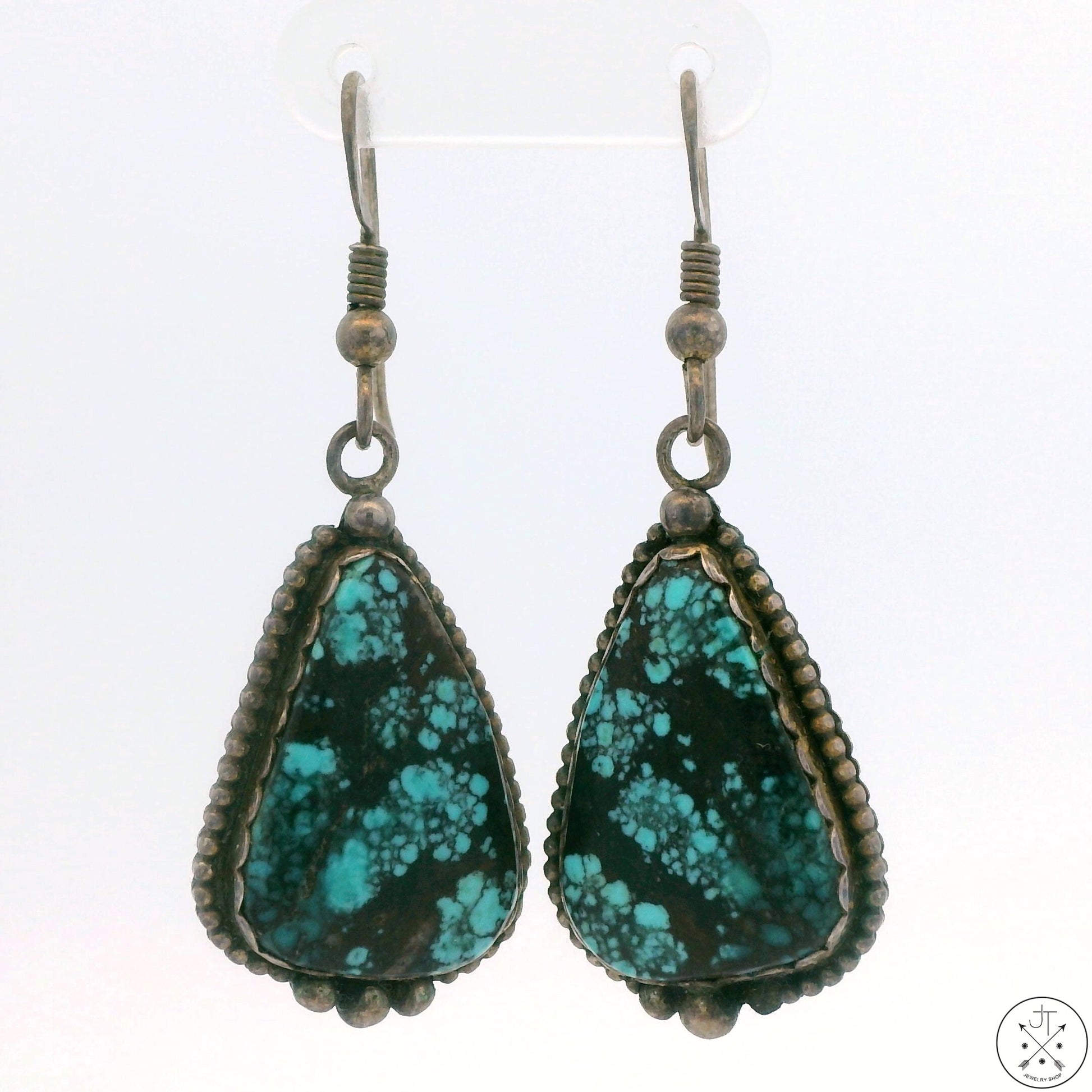A pair of sterling silver dangle earrings featuring a matrix turquoise pattern with spiderweb design, signed by TAMstar.