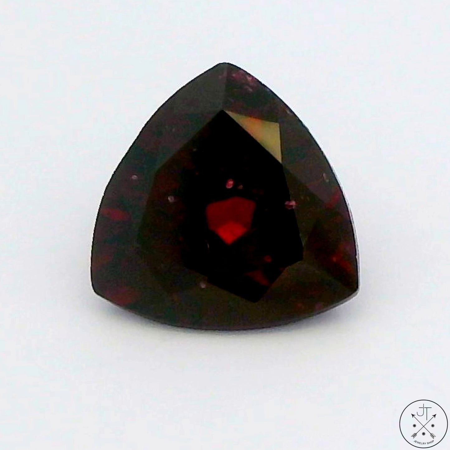 A faceted trillion-cut natural Rhodolite Garnet gemstone with a deep purplish red color.