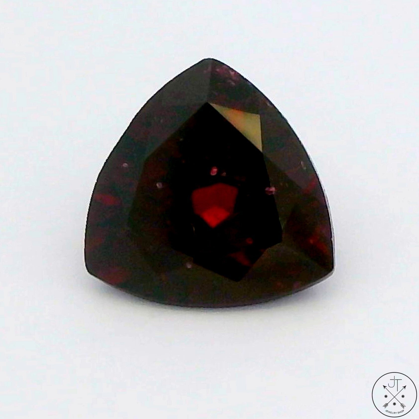A faceted trillion-cut natural Rhodolite Garnet gemstone with a deep purplish red color.