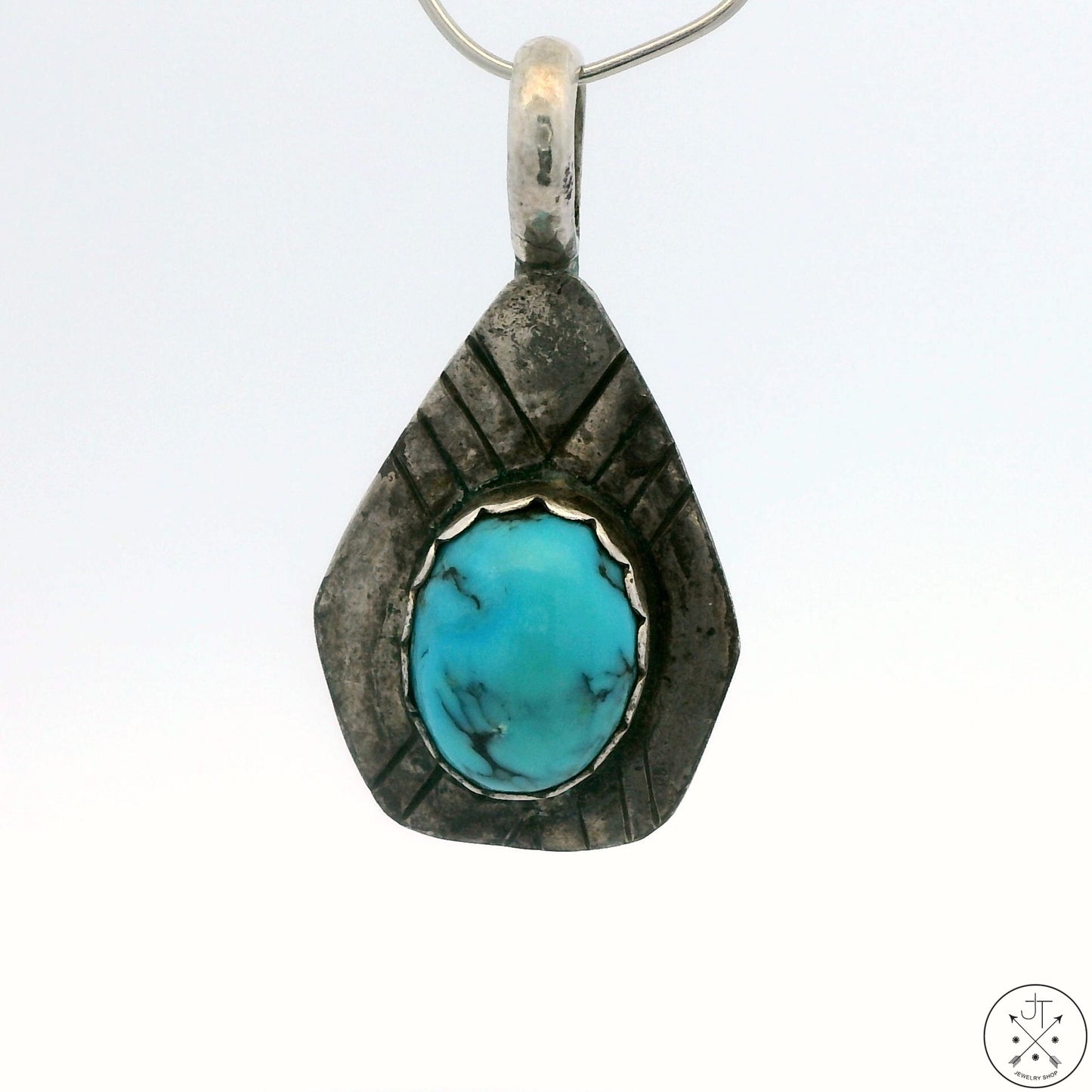 A Sterling Silver pendant with a Dyer Blue Turquoise centerpiece, etched on the back with a signature.