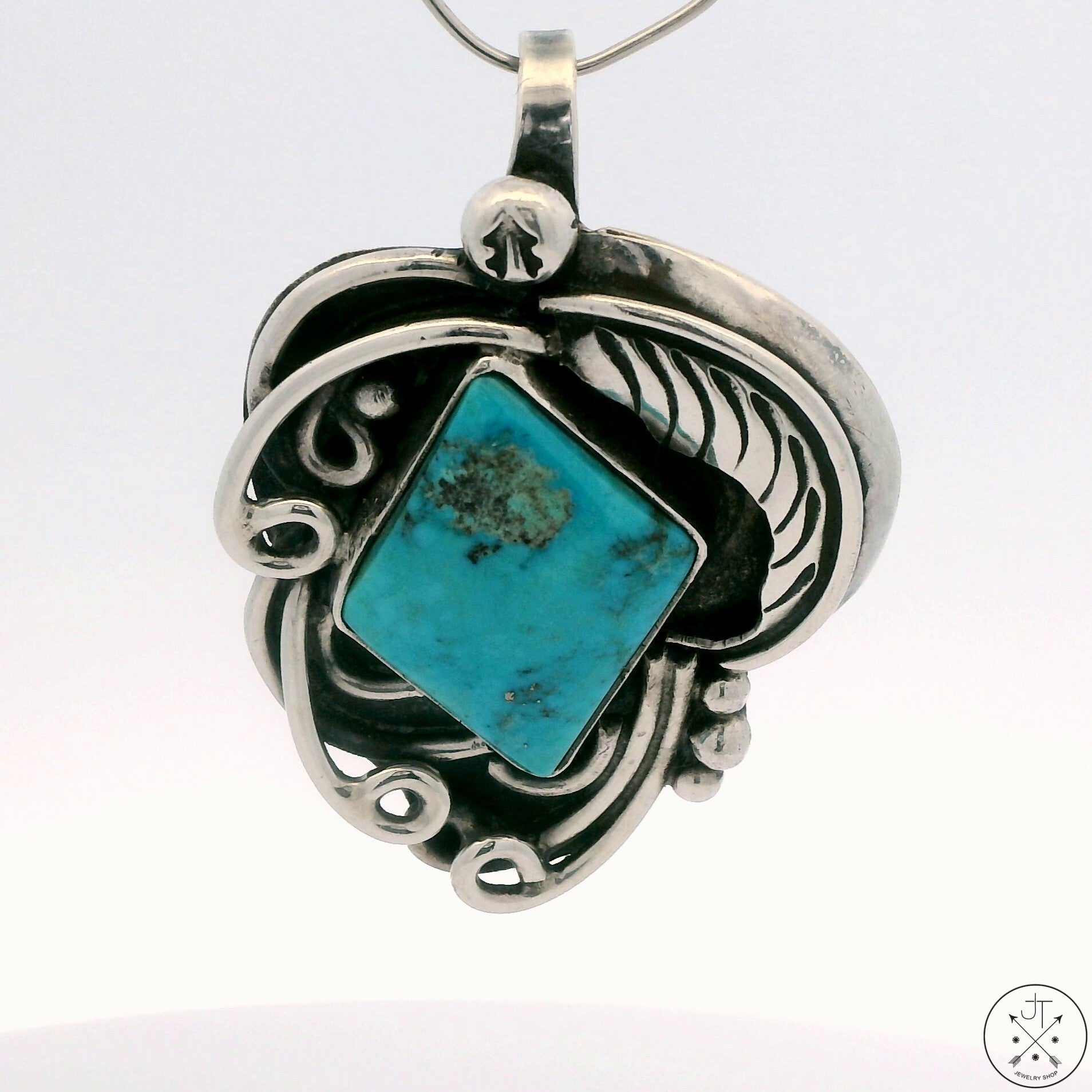 A Sterling Silver Navajo pendant featuring a square-shaped Santa Rita turquoise signin, with a hook bale for attaching to a chain.