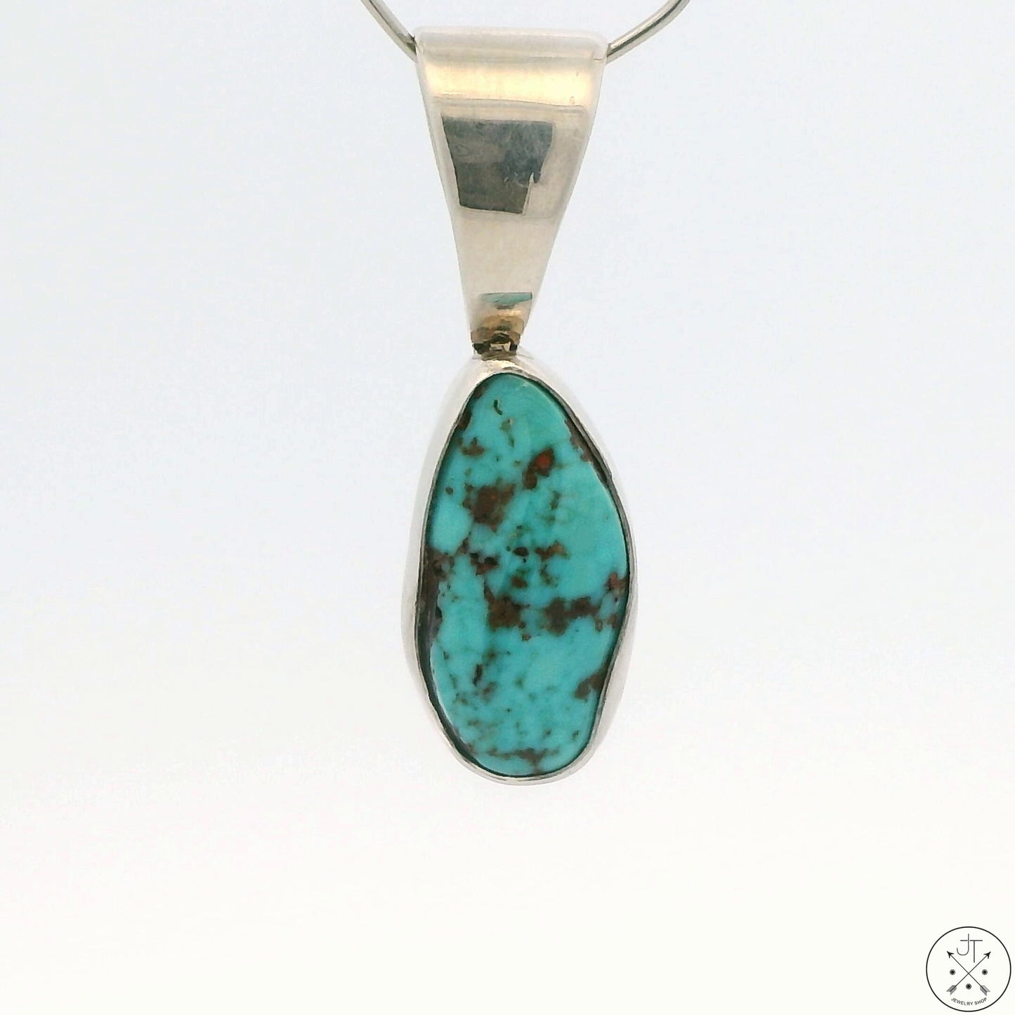 A Sterling Silver pendant featuring a teardrop-shaped Red Mountain Turquoise cabochon with a silver cap and a chain.