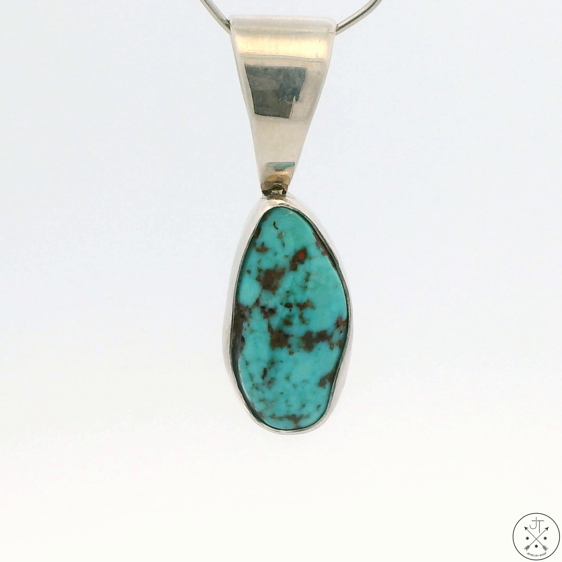 A Sterling Silver pendant featuring a teardrop-shaped Red Mountain Turquoise cabochon with a silver cap and a chain.