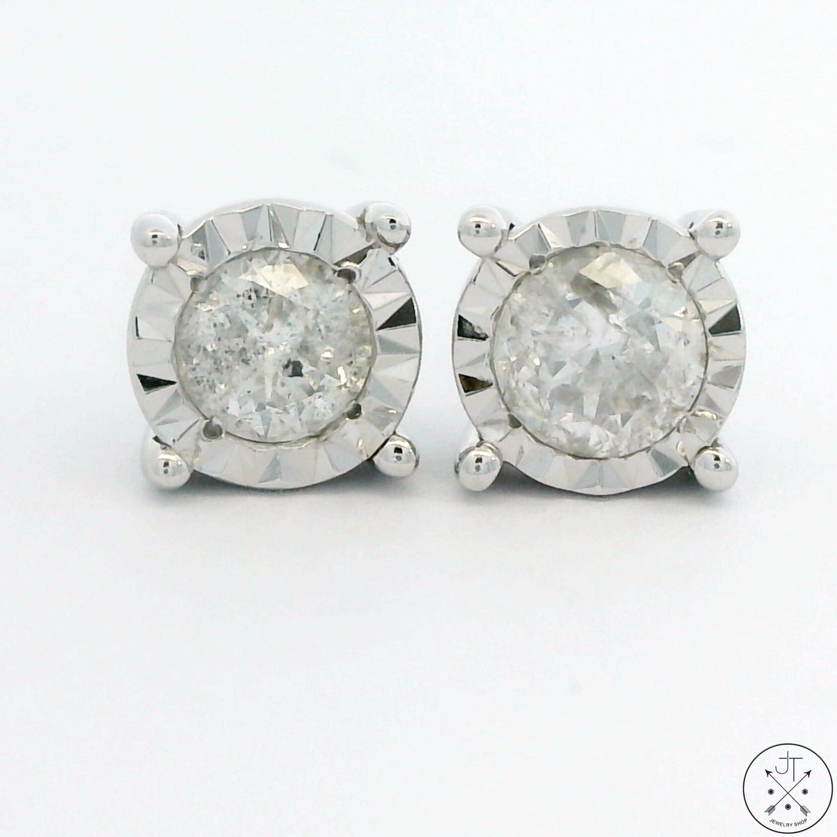 A pair of 10k white gold stud earrings with illusion settings and a total of 1/2 carat of diamonds, featuring J-color and I2-clarity diamonds.