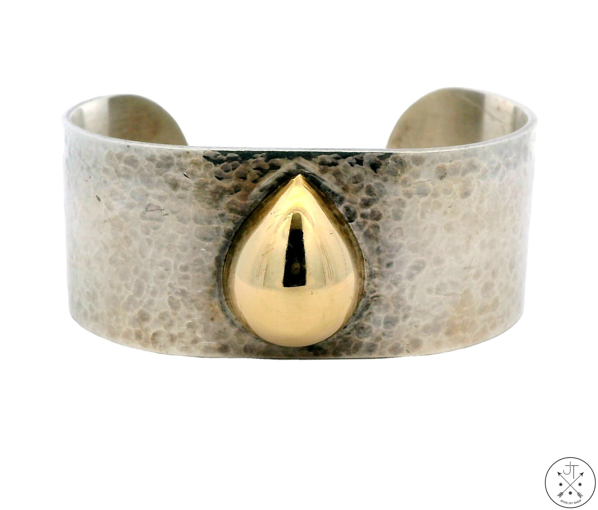 A vintage hammered sterling silver cuff bracelet with a 14k yellow gold teardrop set in the center, displayed against a white background.