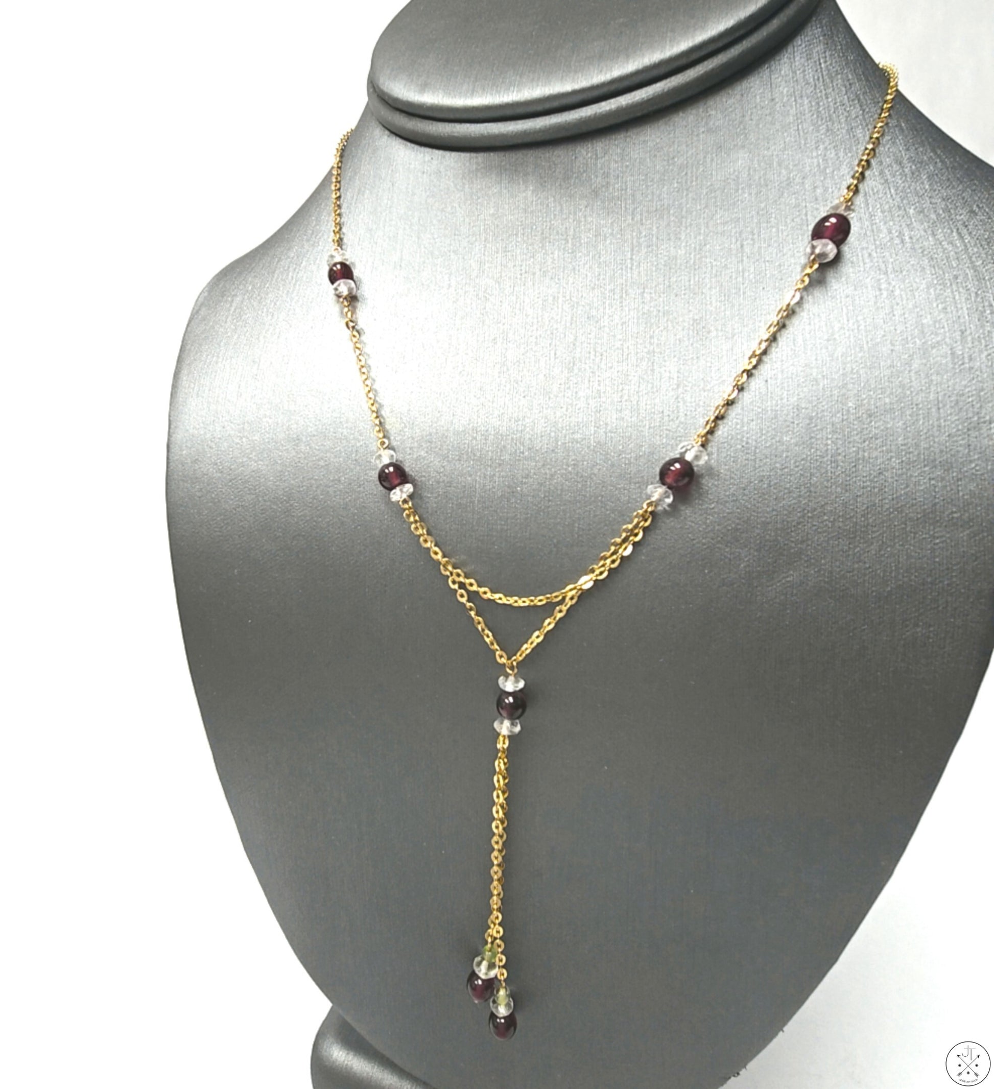 A vintage 14k yellow gold necklace featuring a station necklace lariat with natural garnet and quartz beads, displayed on a mannequin bust.