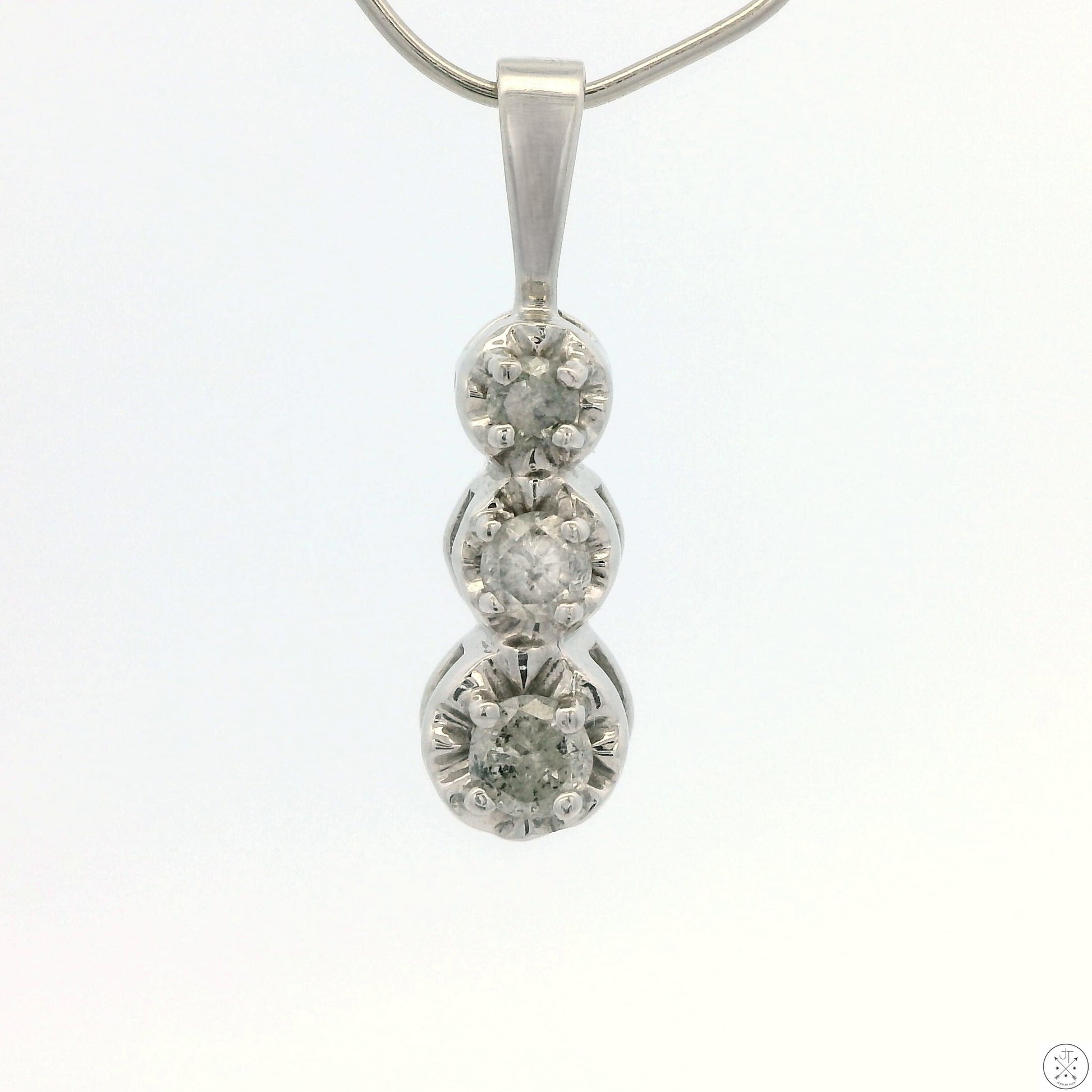 A 10k white gold pendant with three round diamonds mounted in a vertical formation.