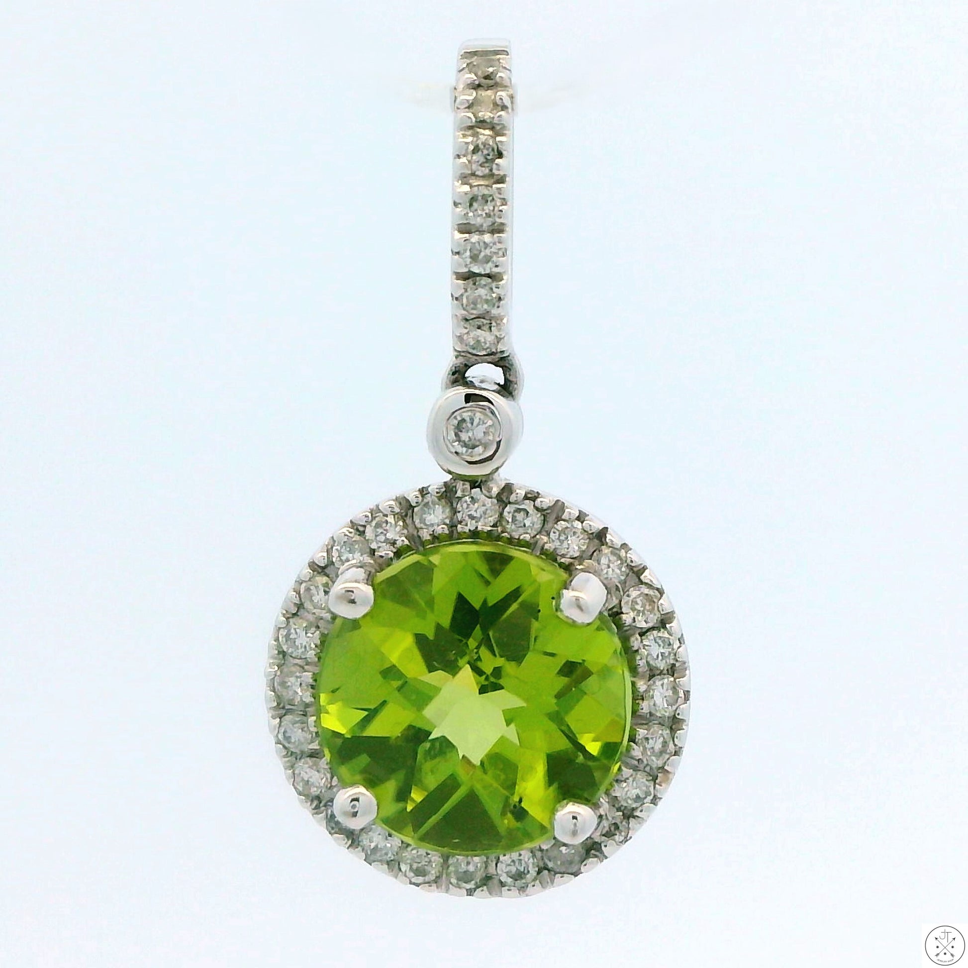 A 14k white gold pendant featuring a large green peridot gemstone with a halo of smaller diamonds around it, attached to a large bale.