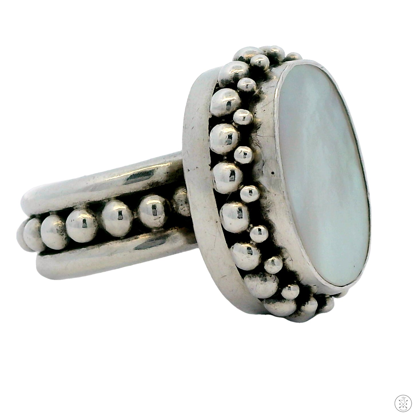 A sterling silver ring with an oval-shaped mother of pearl center stone and a modernist design, featuring a band of small raised dots around the circumference.