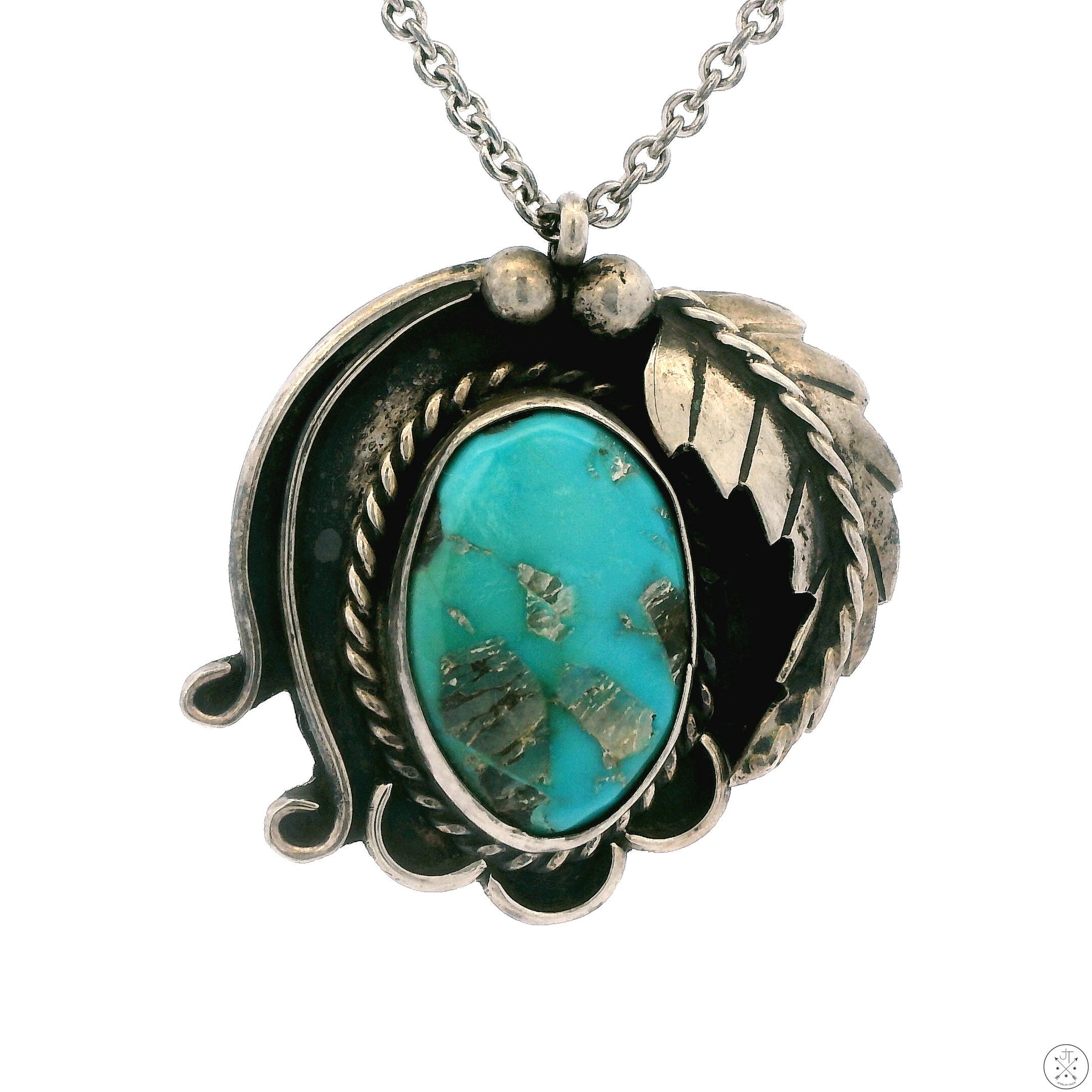 A vintage Zuni sterling silver pendant with a large turquoise cabochon set in a floral-like design with intricate details, attached to a 24 inch silver chain.
