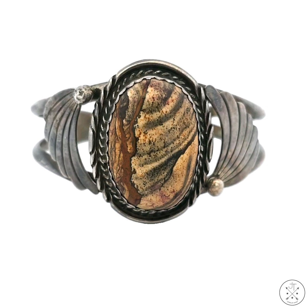 Vintage sterling silver cuff bracelet with a central Biggs Jasper stone, featuring a natural landscape-like pattern with browns and greys, stamped with the double-feather makers mark of Navajo artist Sandy 'Two Feathers' Sangster.