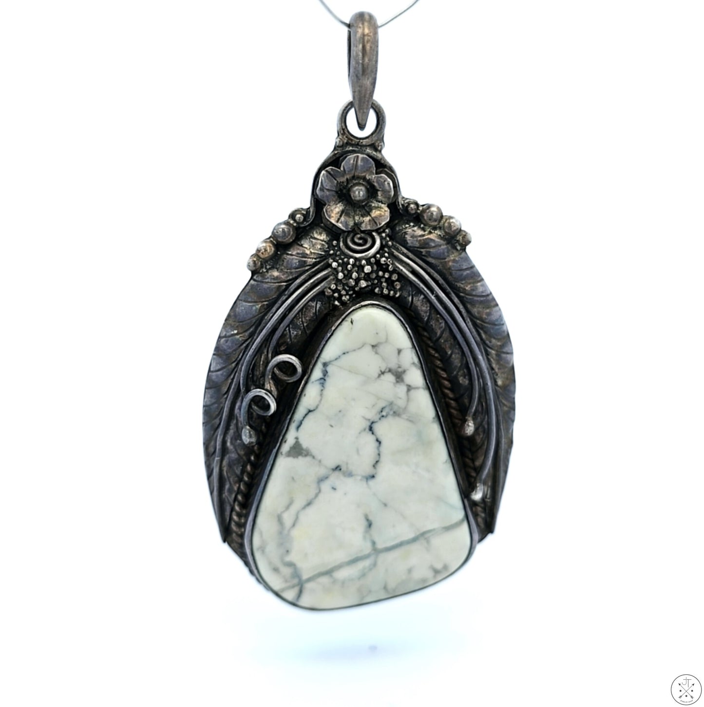 A vintage sterling silver pendant featuring a large white buffalo cabochon with a floral and leaves mounting, viewed against a neutral background.