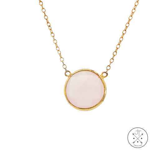 Necklace with a pink pendant and gold chain on a white background