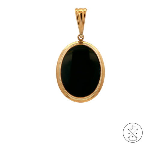A gold oval pendant featuring a smooth, polished black onyx stone, shown against a plain white background with a small circular brand logo in the bottom right corner.