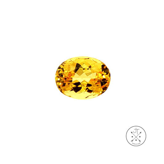An oval-cut golden beryl is shown on a plain white background with a small circular logo in the bottom right corner.