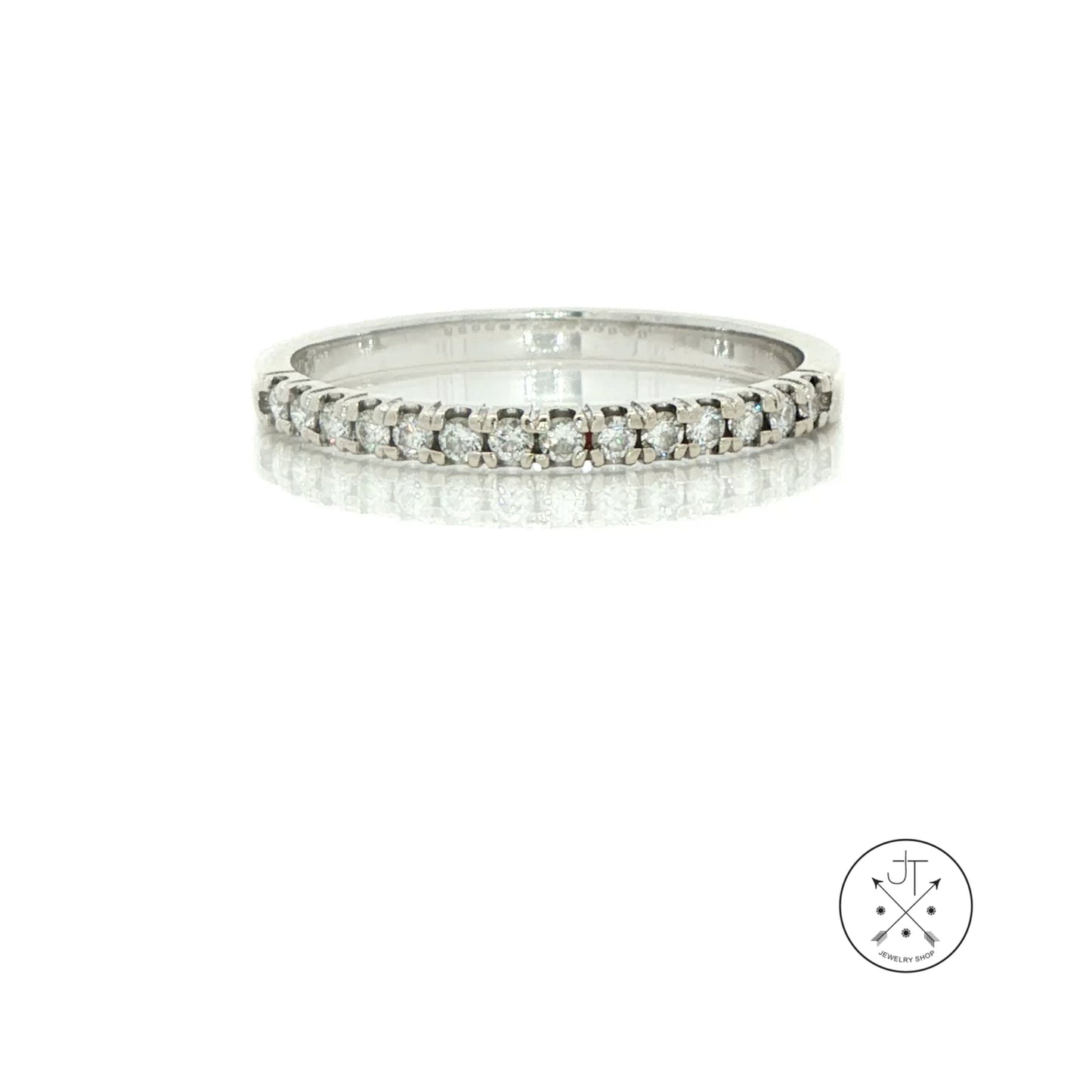 A silver diamond eternity ring with a continuous row of round-cut diamonds set in a polished white gold band, displayed on a reflective white surface against a white background.