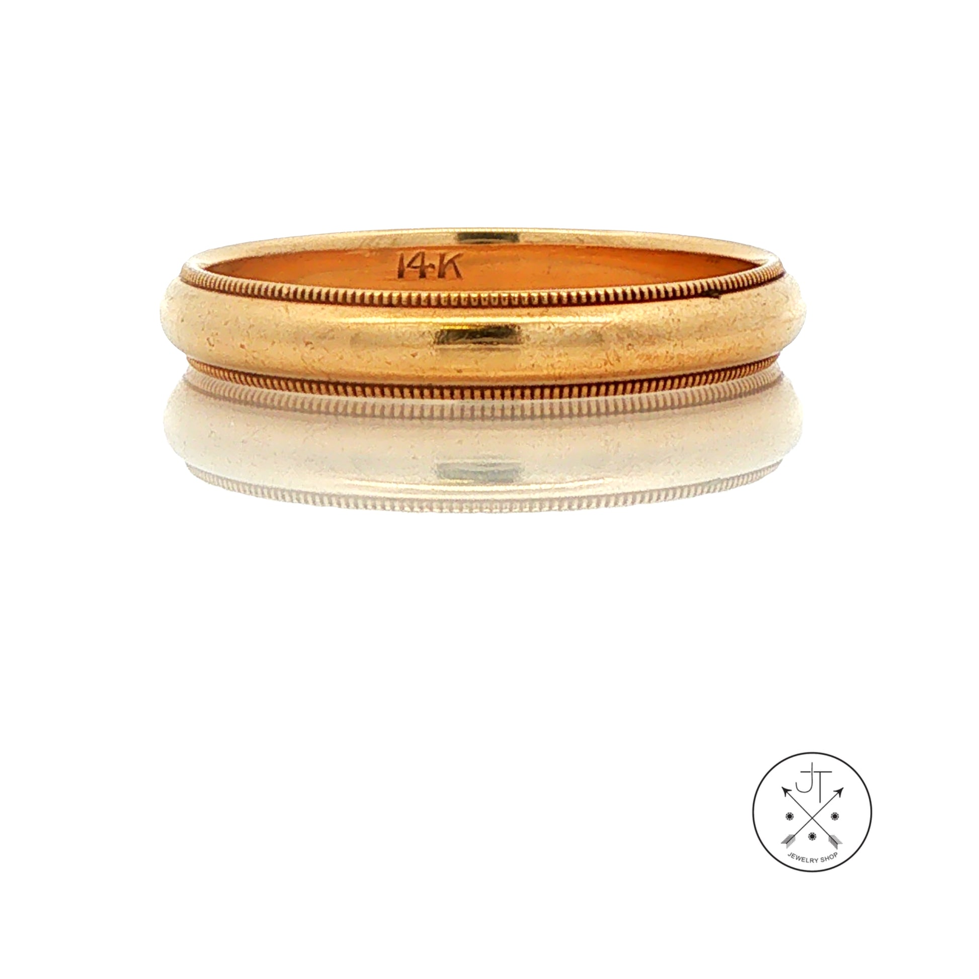 A vintage yellow gold band ring with a textured milgrain outer edge and a smooth inner band, displayed on a reflective white surface. The inside of the ring is stamped with '14K'.