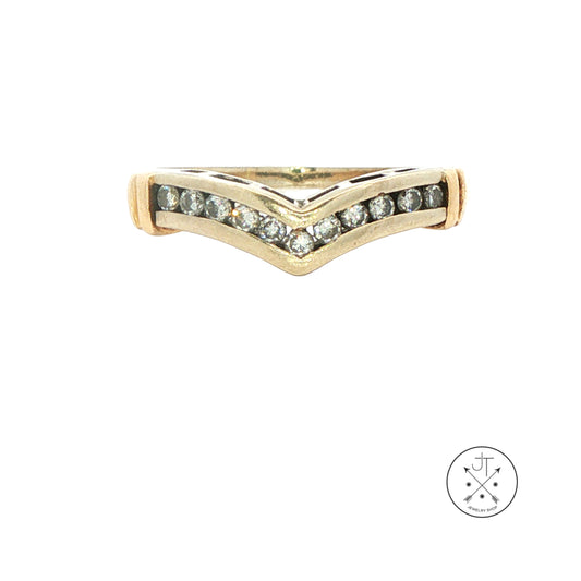 A vintage white gold ring with a chevron V-shaped design, featuring a row of small diamonds on the front. The ring is displayed on a clean white background with a circular logo in the bottom right corner.
