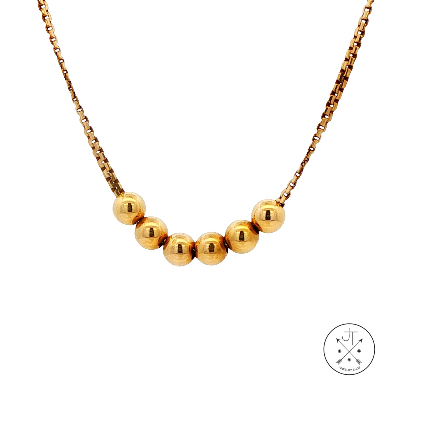 A gold beaded necklace featuring six polished spherical beads on a fine gold chain, shown against a plain white background with a small circular brand logo in the bottom right corner.