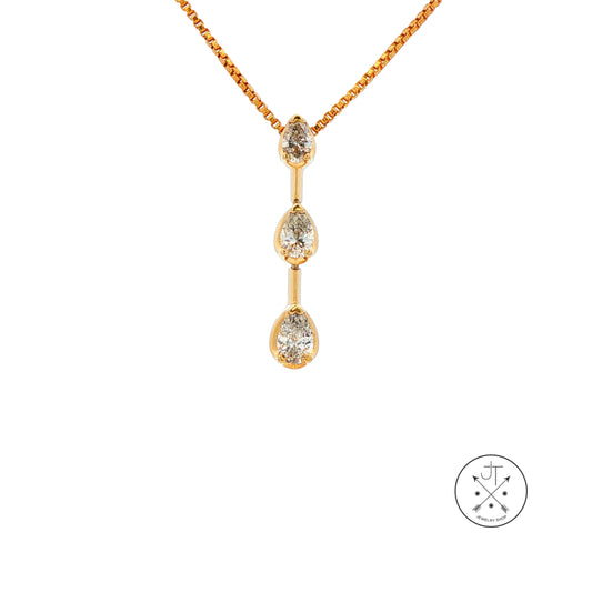 A gold pendant necklace featuring three vertically aligned pear-cut natural diamonds on a gold chain, shown against a plain white background with a small circular brand mark in the lower right corner.
