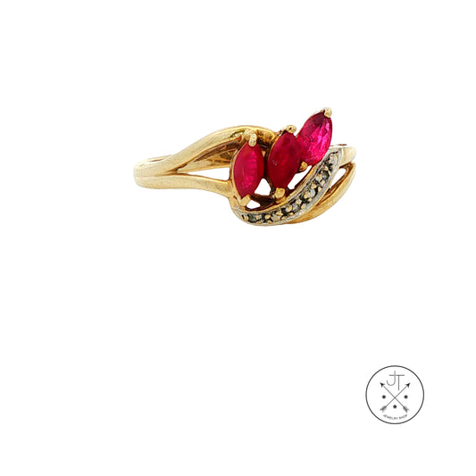 A yellow gold ring featuring three marquise-cut rubies in the center, accented by a curved row of small diamonds, shown on a plain white background with a circular logo in the bottom right corner.