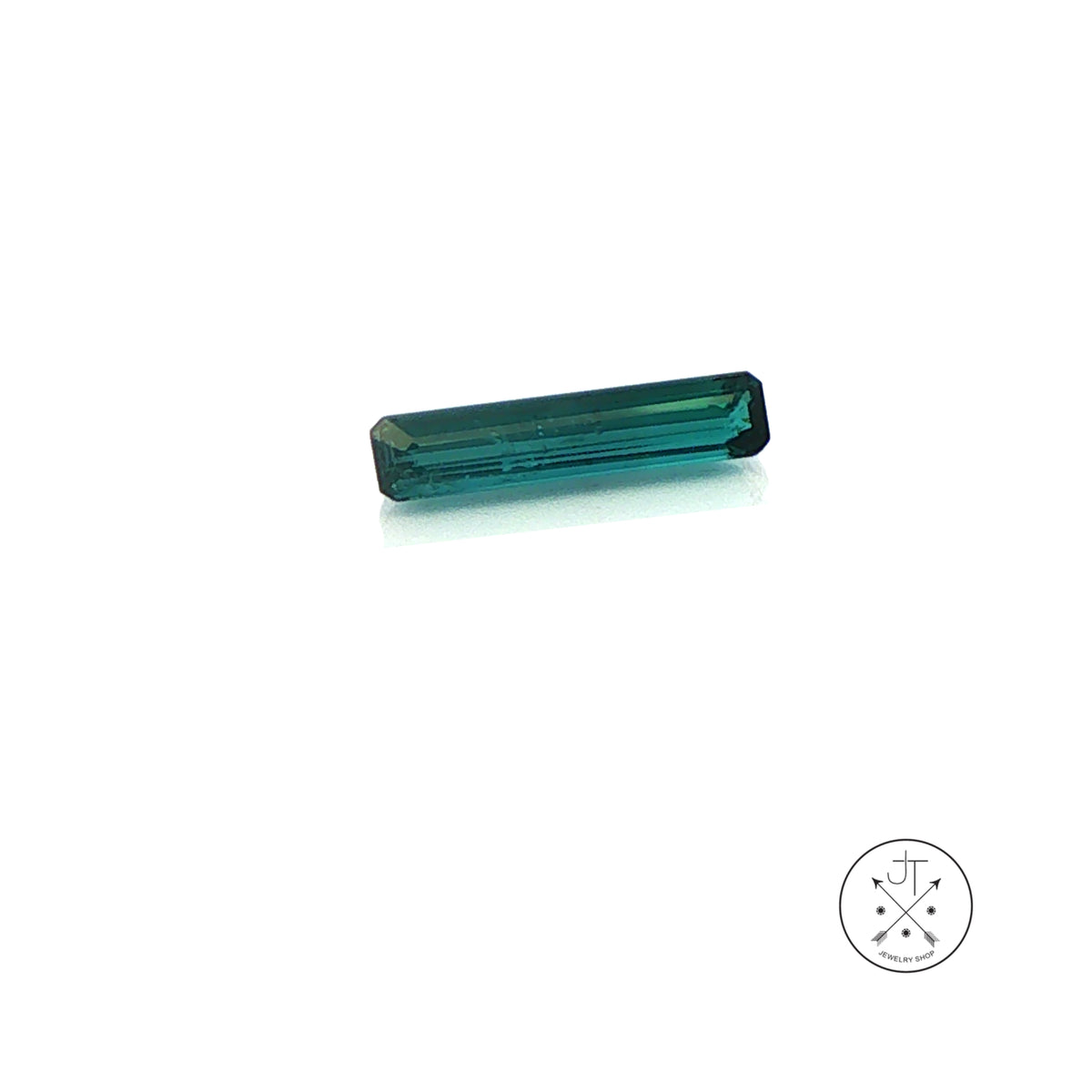 A single rectangular emerald-cut Indicolite Tourmaline gemstone on a clean white background, with a small circular logo in the bottom right corner.